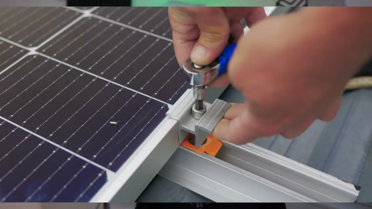 Installation d'un panneau solaire, serrage de la fixation sur le rail du toit